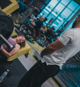 A supportive gym partner assisting a beginner with proper lifting form during a strength workout.