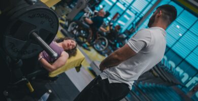 A supportive gym partner assisting a beginner with proper lifting form during a strength workout.