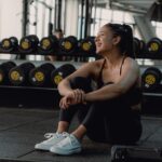 Woman resting and laughing during a gym session to recover from a fitness plateau.