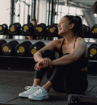 Woman resting and laughing during a gym session to recover from a fitness plateau.