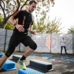 man in black crew neck t-shirt and black shorts running on blue and white trampoline