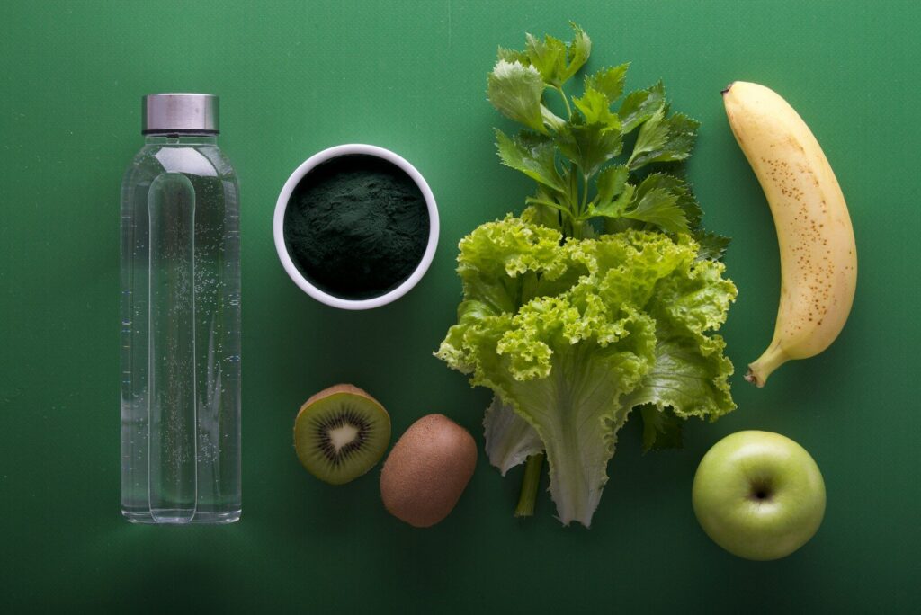 Fresh vegetables, kiwi, and water for optimal nutrition and fitness recovery.