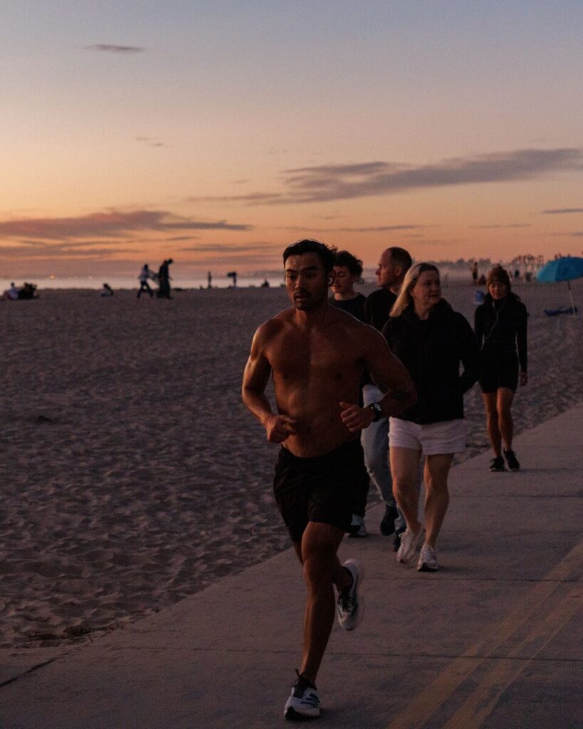 People jogging on a beach path at sunset