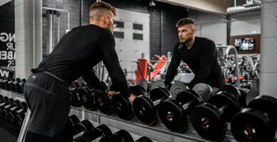 man in black long sleeve shirt and black pants carrying black dumbbell