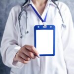 person in white and blue medical scrub holding blue and white card