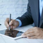 a man in a suit writing on a tablet