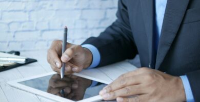 a man in a suit writing on a tablet