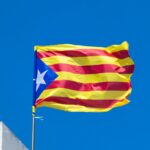 A catalan flag flies proudly against a blue sky.