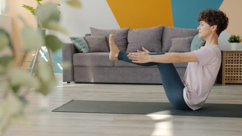 A male athlete performing a controlled, gentle hamstring stretch on a yoga mat, illustrating the importance of proper warm-ups to avoid injury.