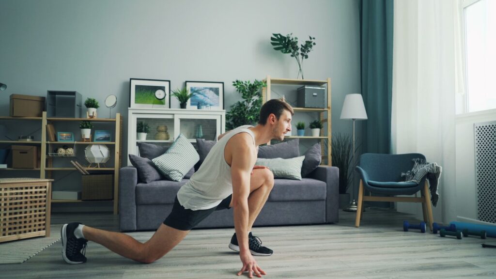 A person in athletic wear performing a focused bodyweight squat in a bright, modern, minimalist living room with natural light.