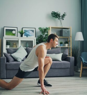 A person in athletic wear performing a focused bodyweight squat in a bright, modern, minimalist living room with natural light.