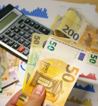 A person holding a bunch of money next to a calculator