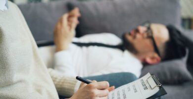 a person laying on a couch writing on a piece of paper